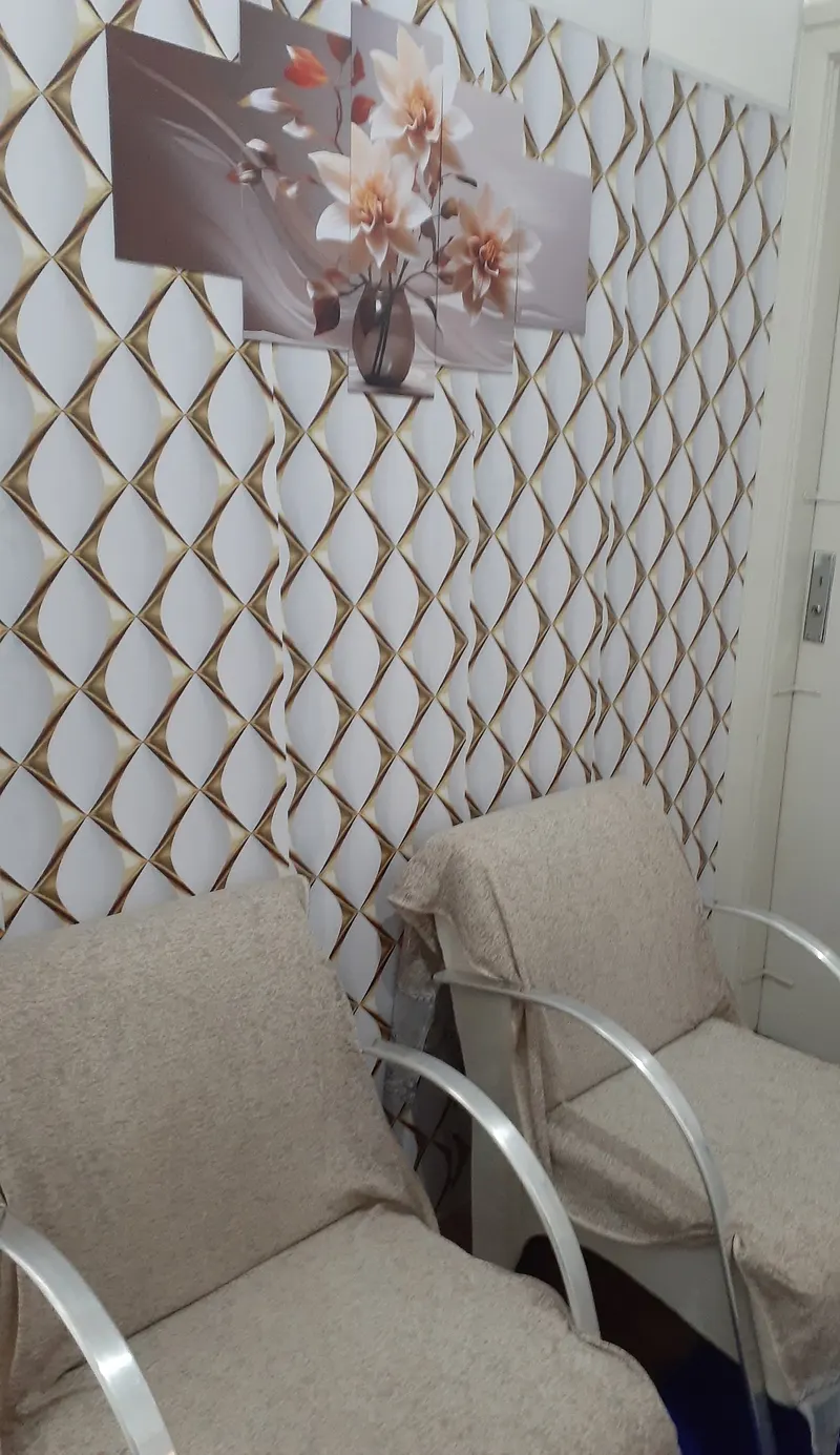 Recepção do Espaço Jaqueline, com duas poltronas bege e um quadro de flores na parede